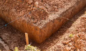 Wyznaczone wykopy pod fundamenty, z widocznymi nićmi wyznaczającymi linie i drewnianym palikiem.