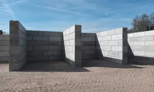 Betonowy murek oporowy w kształcie litery L, tworzący skarpy na placu budowy.