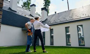 Architekt i budowlaniec omawiają plany przed nowoczesnym domem w budowie. Mieszkanie w domu bez odbioru to wyzwanie, ale i szansa na stworzenie wymarzonego wnętrza.