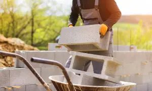Budowa domu w toku. Pracownik układa pustaki, przygotowując się do rozliczenia budowy domu z urzędem skarbowym.