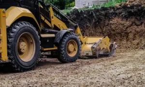 Koparka pracuje nad tym, jak wyrównać działkę, usuwając ziemię z wykopu.
