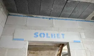 Dylatacja betonu na budowie, widoczna niebieska pianka montażowa i logo SOLBET na nadprożu.