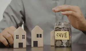 Dwa drewniane domki i słoik z monetami z napisem "SAVE". Czy mieszkanie może być wkładem własnym?