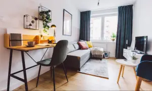 Przytulny salon z biurkiem, kanapą i roślinami. Idealne miejsce do pracy i relaksu, gdzie można też pomyśleć o podatku od wynajmu mieszkania.