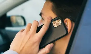 Mężczyzna w samochodzie rozmawia przez telefon. Czy bank dzwoni do klienta?