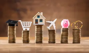 Stosy monet symbolizują cele życiowe: edukację, zakupy, dom, podróże, oszczędności i małżeństwo. Limit odnawialny a debet – jak zarządzać finansami?