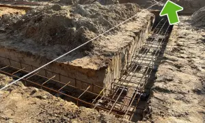 Wykonano wykopy pod fundamenty, w których widać zbrojenie. W tle plac budowy z hałdami ziemi i elementami konstrukcji. Widać ławy ciesielskie.