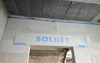 Dylatacja betonu na budowie, widoczna niebieska pianka montażowa i logo SOLBET na nadprożu.