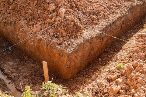 Wyznaczone wykopy pod fundamenty, z widocznymi nićmi wyznaczającymi linie i drewnianym palikiem.