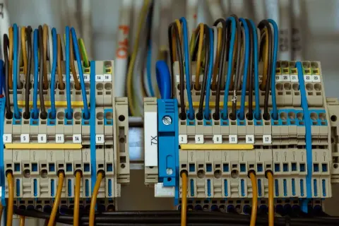 Dwa przyłącza energetyczne do jednej działki, z wieloma przewodami w różnych kolorach, podłączonymi do zacisków.