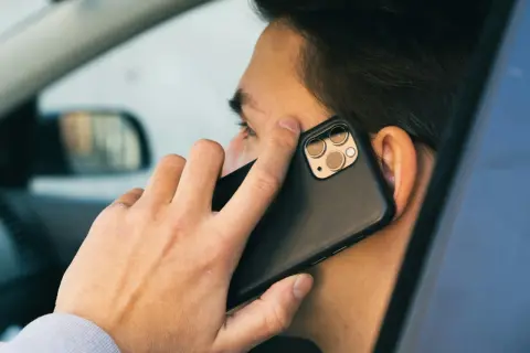 Mężczyzna w samochodzie rozmawia przez telefon. Czy bank dzwoni do klienta?