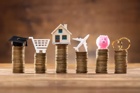 Stosy monet symbolizują cele życiowe: edukację, zakupy, dom, podróże, oszczędności i małżeństwo. Limit odnawialny a debet – jak zarządzać finansami?