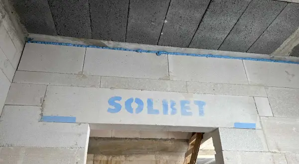 Dylatacja betonu na budowie, widoczna niebieska pianka montażowa i logo SOLBET na nadprożu.