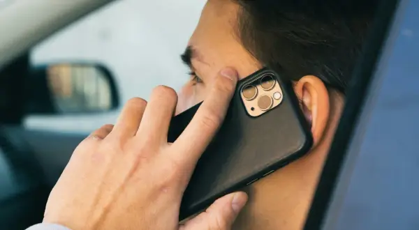 Mężczyzna w samochodzie rozmawia przez telefon. Czy bank dzwoni do klienta?
