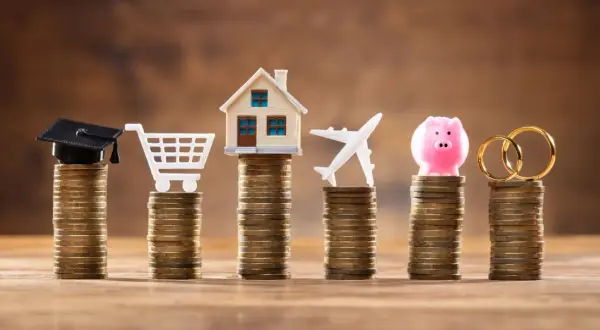 Stosy monet symbolizują cele życiowe: edukację, zakupy, dom, podróże, oszczędności i małżeństwo. Limit odnawialny a debet – jak zarządzać finansami?