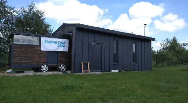 Mobilny garaż bez pozwolenia 70m2, z drewnianą częścią na przyczepie i ciemnoszarą, nowoczesną bryłą.