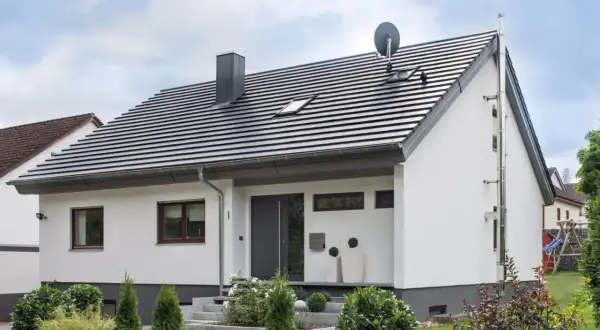 Nowoczesny dom z białymi ścianami i ciemnym dachem o kącie nachylenia dachu 35 stopni. Przed wejściem schody i zadbane rośliny.