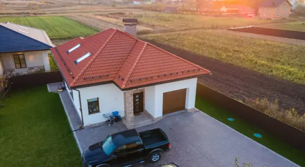 Nowy dom z garażem i dwoma samochodami na podjeździe. Słońce zachodzi nad polami. Może to miejsce będzie przedmiotem umowy darowizny.