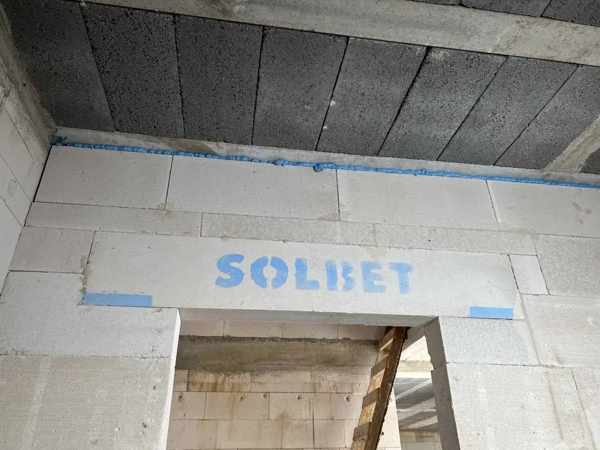 Dylatacja betonu na budowie, widoczna niebieska pianka montażowa i logo SOLBET na nadprożu.