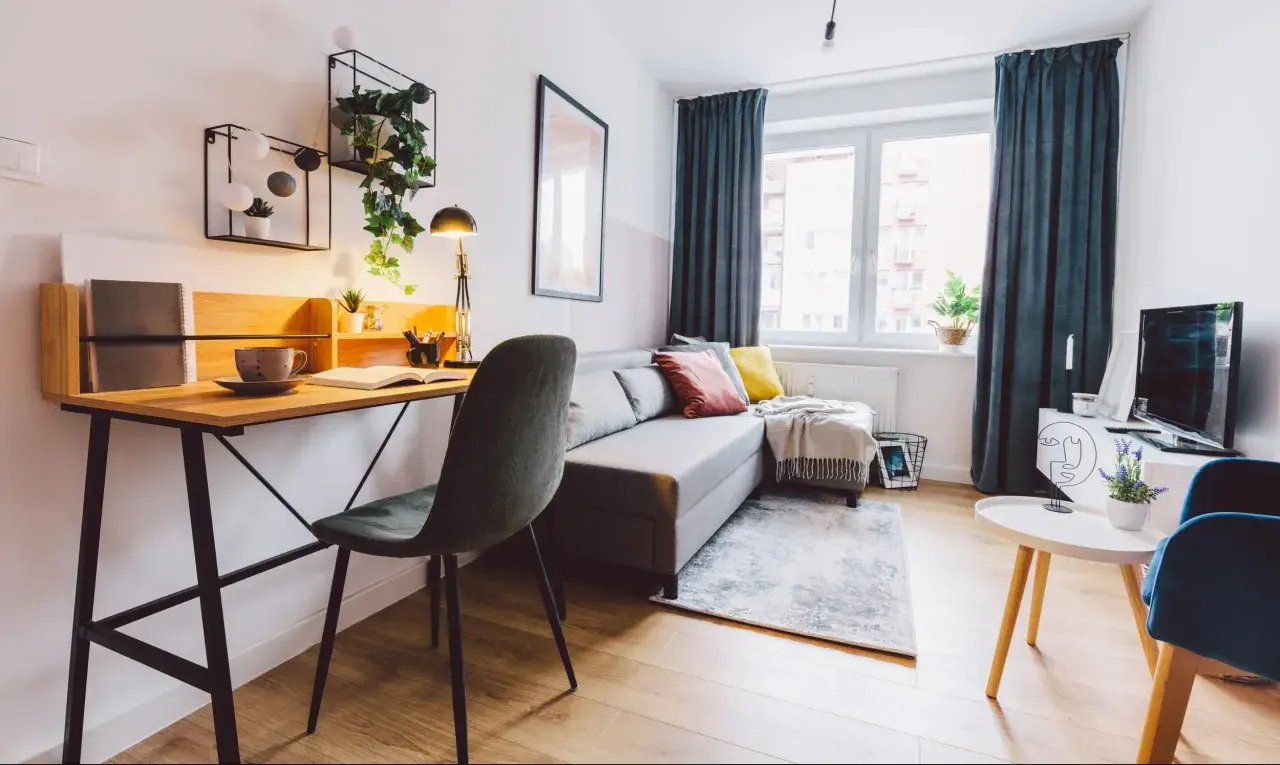Przytulny salon z biurkiem, kanapą i roślinami. Idealne miejsce do pracy i relaksu, gdzie można też pomyśleć o podatku od wynajmu mieszkania.