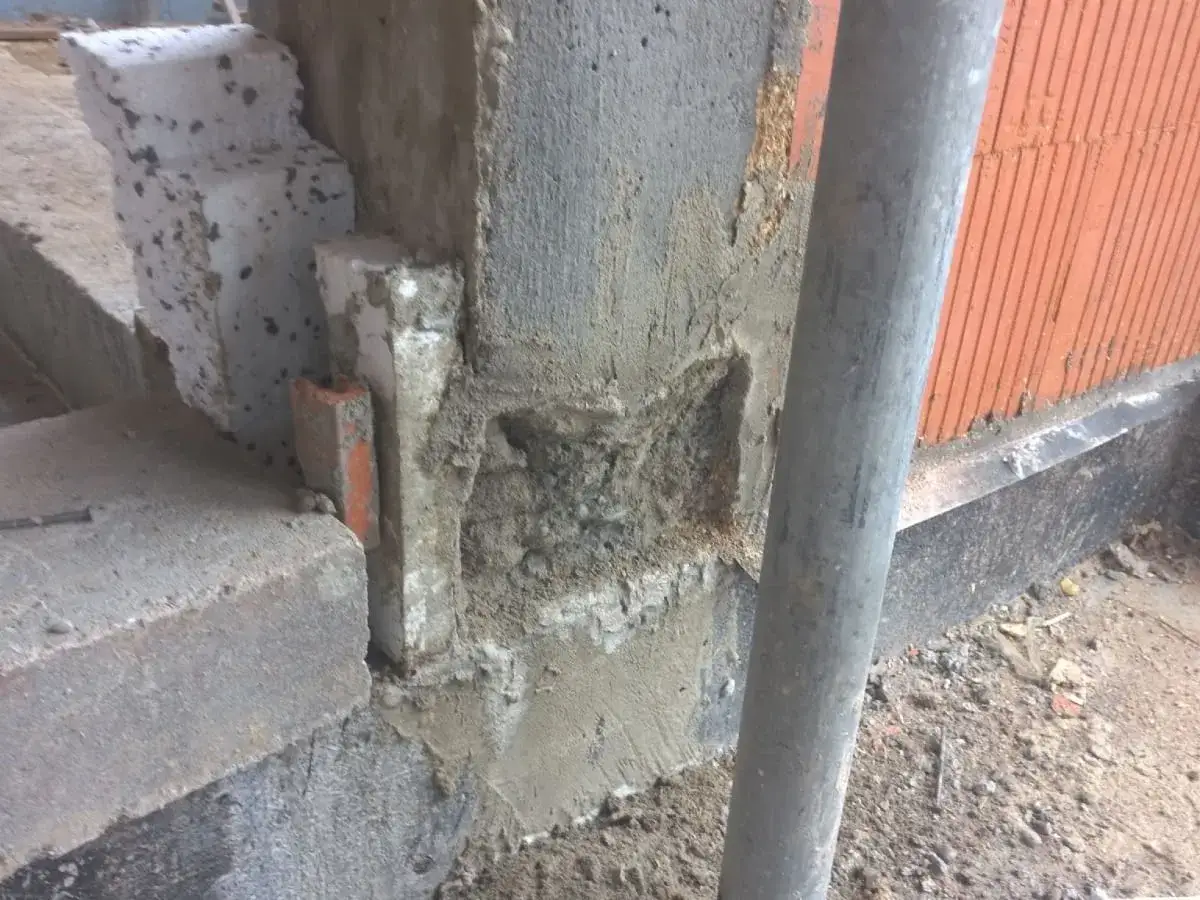 Widoczne ubytki i nier&oacute;wności świadczą o źle zawibrowanym betonie. Widać fragmenty pustak&oacute;w i rurę.