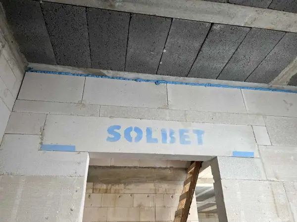 Dylatacja betonu na budowie, widoczna niebieska pianka montażowa i logo SOLBET na nadprożu.