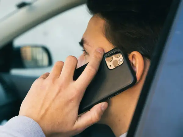Mężczyzna w samochodzie rozmawia przez telefon. Czy bank dzwoni do klienta?