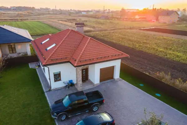 Nowy dom z garażem i dwoma samochodami na podjeździe. Słońce zachodzi nad polami. Może to miejsce będzie przedmiotem umowy darowizny.
